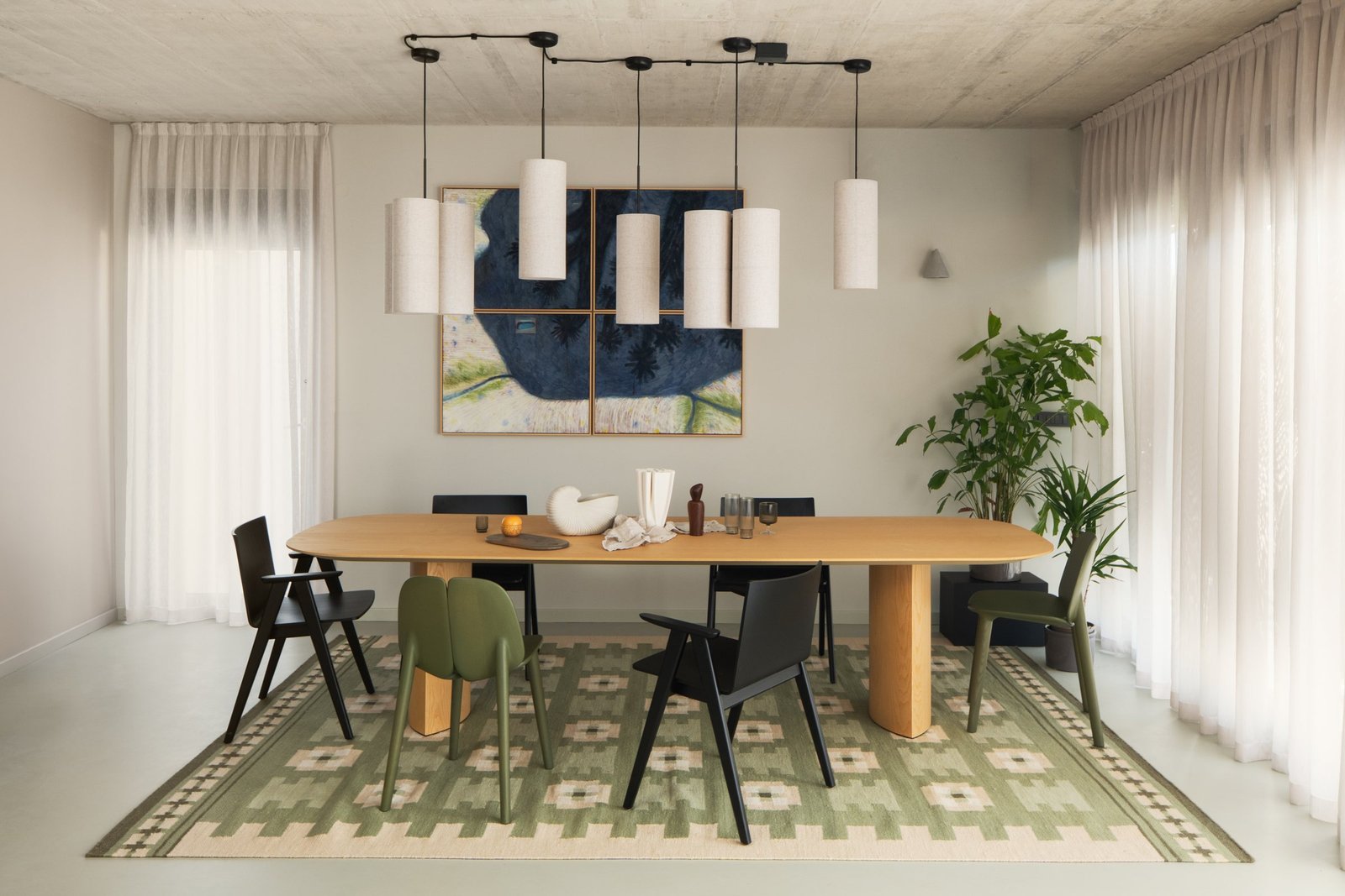Arc House: dining table under white pendant lamps on a green rug