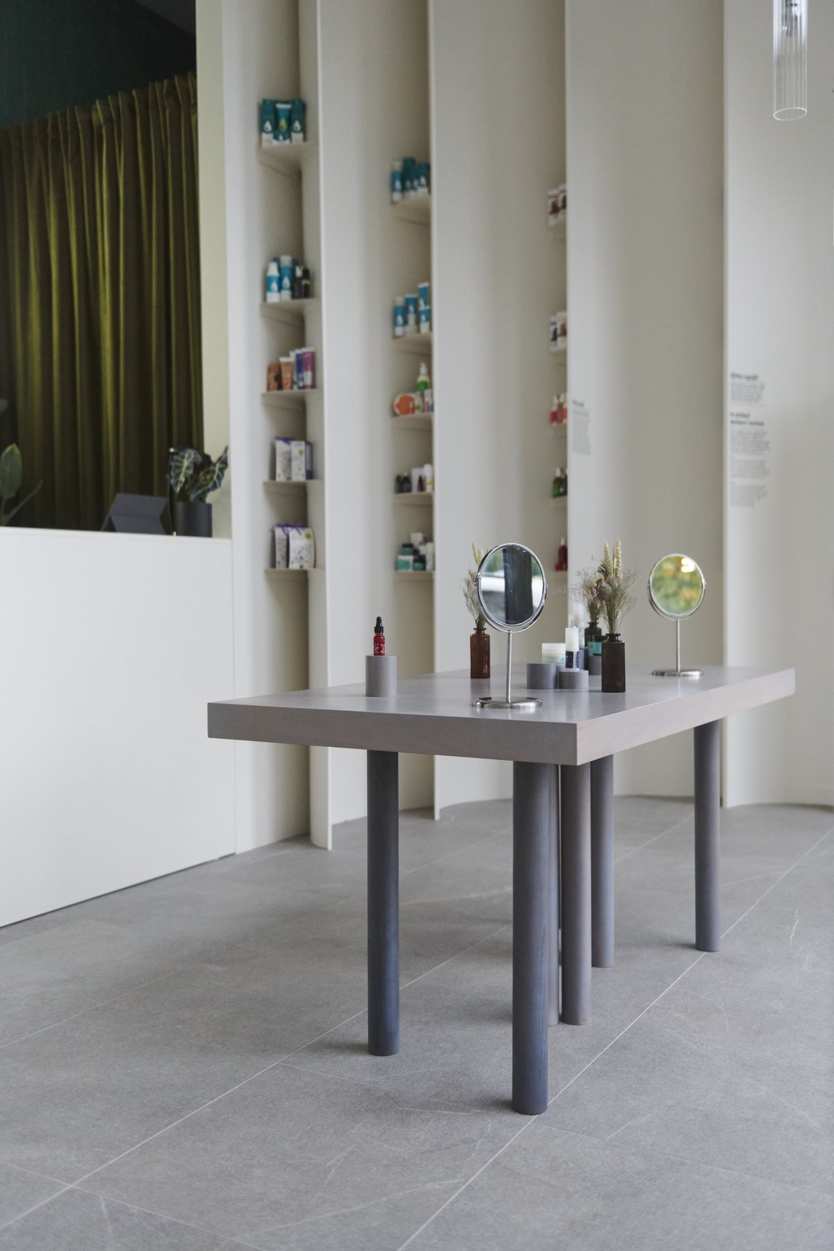 Bio Boutique: grey table on round legs in front of curved white shelving
