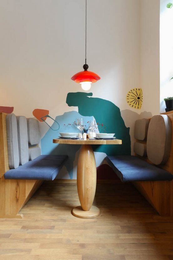 Veganšpek: timber booth with a red pendant lamp and painted mural